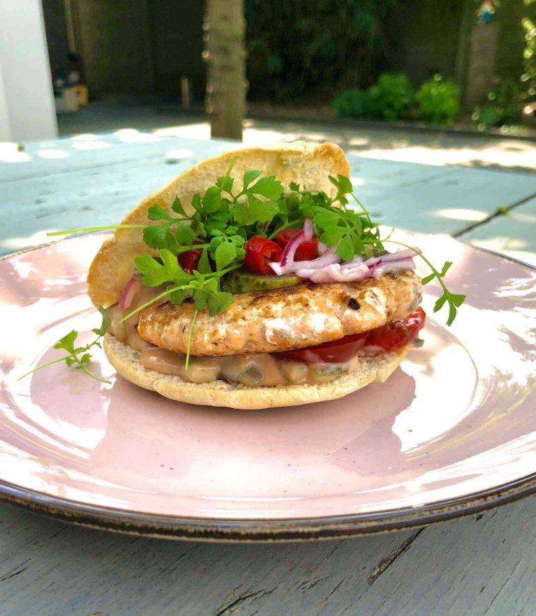 Snelle pita met een zelfgemaakte zalmburger, ingelegde peper en ui en een cocktailsaus
